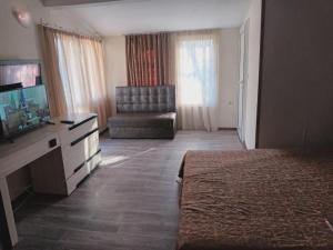 Habitación de hotel con cama, TV y silla en Apartments Devora 1 & bar & restaurant, en Varna