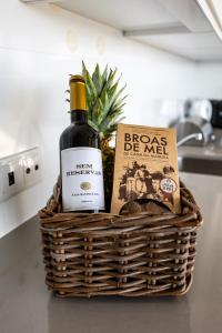 una cesta con una botella de vino y un libro en Carina Villas, en Lourinhã