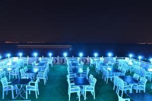 a group of tables and chairs on a balcony at night at Kutlugun Sahil Otel in Akcay