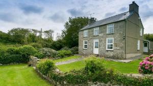 an old stone house with a green yard at Aber in Moelfre