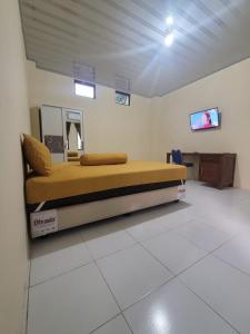 a bedroom with a bed and a tv on a wall at Solo Nadamax City Guest House Syariah in Bonorejo