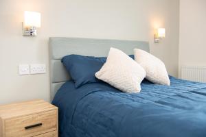 a bed with blue sheets and two pillows on it at Cara Lodge, Comfortable Self Check-in En-suite Guest Rooms in Berwick-Upon-Tweed