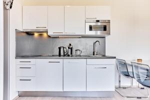 a kitchen with white cabinets and a sink and chairs at SlopeSide apartment in Loučná pod Klínovcem