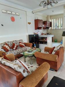 a living room with leather couches and a table at Solo Nadamax City Guest House Syariah in Bonorejo