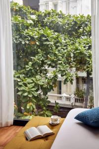 a table with two books and a cup of coffee next to a window at Eliana Signature Hanoi Hotel in Hanoi