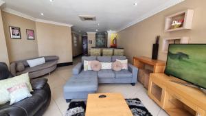 a living room with a couch and a flat screen tv at Accommodation Front - Dazzling 4 Sleeper near Ushaka Marine World in Durban