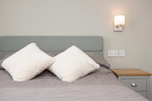 ein Bett mit zwei weißen Kissen darüber in der Unterkunft Cara Lodge, Comfortable Self Check-in En-suite Guest Rooms in Berwick-Upon-Tweed
