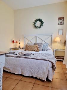 a bedroom with a large white bed with a wreath on the wall at Apartamento rural La Encina Complejo La Fontanina in Mata de Alcántara