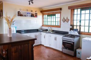 a kitchen with white cabinets and a stove top oven at Wild Amboseli Ndovu Cottage. in Amboseli