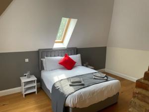 a bedroom with a bed with red pillows and a window at Two Bedroom Duplex Apartment The Priory in St Ives