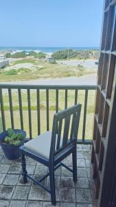 a chair sitting on a porch looking out at the ocean at Beachfront at 22 Settler's Sands in Port Alfred