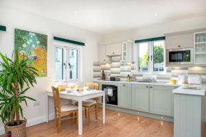 uma cozinha com armários brancos e uma mesa com cadeiras em Luxury Country Cottage, near Tavistock. em Tavistock