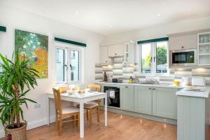a kitchen with white cabinets and a table with chairs at Luxury Country Cottage, near Tavistock. in Tavistock