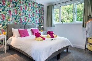 dois bichos de peluche sentados numa cama com almofadas cor-de-rosa em Luxury Country Cottage, near Tavistock. em Tavistock