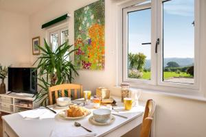 a table with food and drinks on it in front of a window at Luxury Country Cottage, near Tavistock. in Tavistock