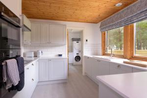 a kitchen with white cabinets and a wooden ceiling at Ballater Bungalow - 4 bed - Beautiful Garden in Ballater