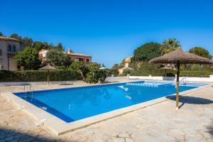 a swimming pool with an umbrella and a house at Casa Stevens in Colonia de Sant Pere