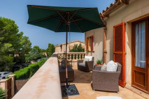 a patio with a green umbrella on a balcony at Casa Stevens in Colonia de Sant Pere