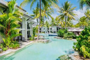 a swimming pool in front of a house with palm trees at Paradise Escape - Poolside Ground Floor - Sea Temple Resort and Spa in Port Douglas