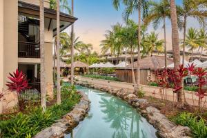 a pool at a resort with palm trees at Paradise Escape - Poolside Ground Floor - Sea Temple Resort and Spa in Port Douglas