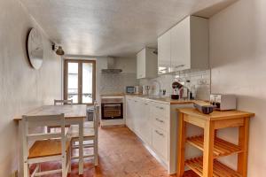 eine große Küche mit weißen Schränken und einem Tisch in der Unterkunft Le Robinson - Classé 3 étoiles in Flins-sur-Seine