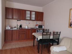 una cocina con armarios de madera y una mesa con sillas. en T-Apartman Hajdúszoboszló, en Hajdúszoboszló