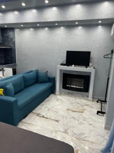 a living room with a blue couch and a fireplace at ΧΑΝΙΟΤΗ LUXURY STUDIOS 2 FIRST SEA BY MAKHMOME in Hanioti