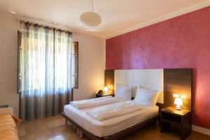 a bedroom with a bed with a red wall at Villa Ginevra Resort Agrituristico in Ficarra