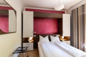 a bedroom with a large bed and a pink wall at Villa Ginevra Resort Agrituristico in Ficarra