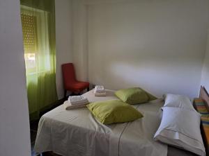 a bedroom with a bed with two pillows and a red chair at Villa Gatto Camilla in Rometta Marea