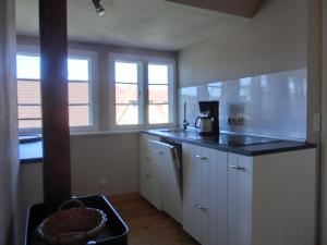 a kitchen with white cabinets and a black counter top at Strandstraße 60 Ferienwohnung S16 in Graal-Müritz +6 photos