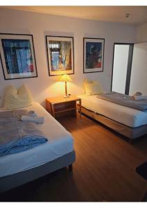 ein Schlafzimmer mit 2 Betten und einem Tisch mit einer Lampe in der Unterkunft Estelada Boarding Houses in München