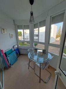 ein Wohnzimmer mit einem Glastisch und Stühlen in der Unterkunft Apartamento en playa de Valdelagrana in El Puerto de Santa María