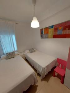 Zimmer mit 2 Betten und einem roten Stuhl in der Unterkunft Apartamento en playa de Valdelagrana in El Puerto de Santa María