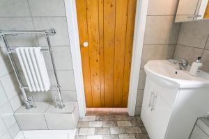 a bathroom with a toilet and a wooden door at Cwter Hywel in Coedana