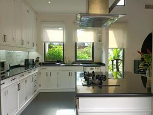 a kitchen with white cabinets and black counter tops at Beautiful villa walking distance from Bangtao Beach in Bang Tao Beach