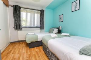 two beds in a room with blue walls and wooden floors at Peaceful Urban Getaway in Liverpool