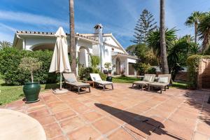 a patio with chairs and an umbrella and a house at Nice villa caribplaya in Marbella
