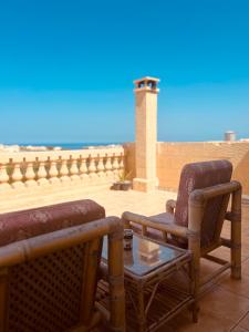 two chairs and a table on a balcony with the beach at Narcisa Farmhouse B&B in Nadur