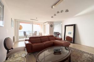 sala de estar con sofá de cuero marrón y mesa en Impresionante Apartamento delante del Mar en Vilassar de Mar