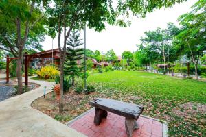 a wooden bench sitting on a brick path in a park at ชานไม้ รีสอร์ท 