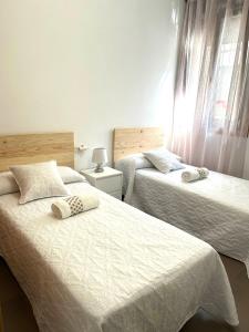 1 dormitorio con 2 camas con sábanas blancas y ventana en O LAR DE MARTINA, en Redondela