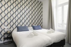 two twin beds in a room with a large window at Villa Pax 1 et 2 La Bourboule in La Bourboule