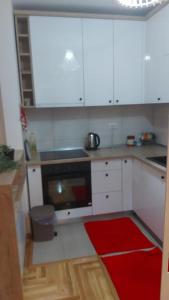 a kitchen with white cabinets and a red rug at Anja in Lukavica