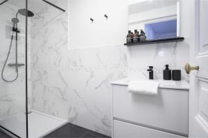 a white bathroom with a shower and a sink at Villa Pax 1 et 2 La Bourboule in La Bourboule +20 photos