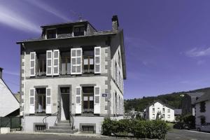 a building with white shutters and a statue in front of it at Villa Pax 1 et 2 La Bourboule in La Bourboule