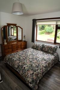 a bedroom with a bed and a dresser and a window at Number 19 Heart Of The Glens in Cushendall