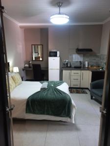 ein Schlafzimmer mit einem Bett mit einer grünen Decke darauf in der Unterkunft Esperance Guesthouse in Upington