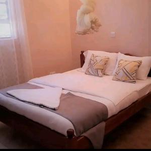Elegantly furnished studio في نيروبي: سرير عليه أغطية ووسائد بيضاء