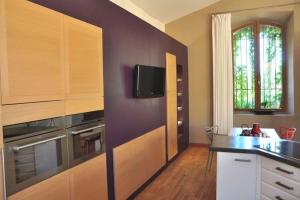 cocina con armarios de madera y TV en la pared en loft zen et design, spacieux, en Graveson